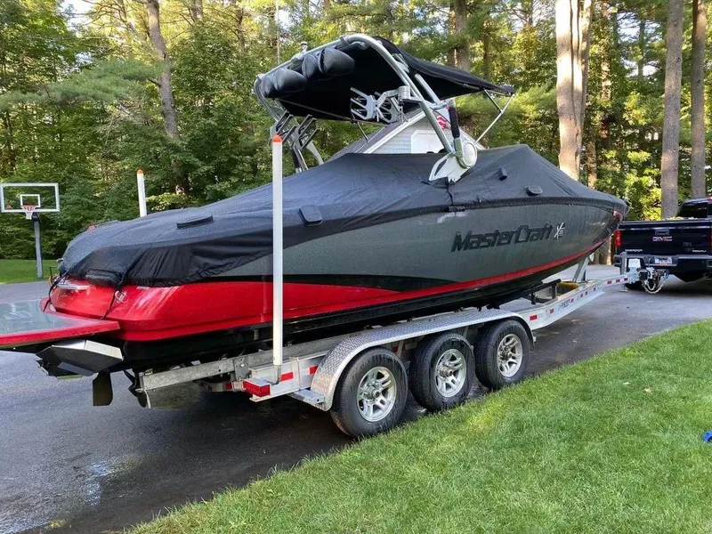 Slide: The Image of 2015 MasterCraft X55 boat on a trailer with a protective cover in a driveway. - 6