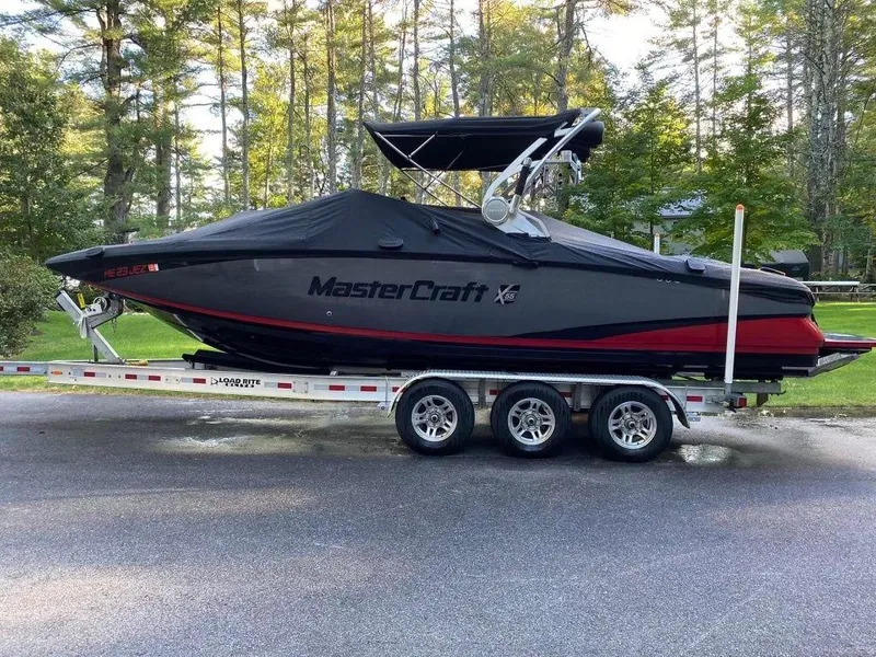 Slide: The Image of 2015 MasterCraft X55 boat on a triple-axle trailer, covered and parked outdoors. - 7