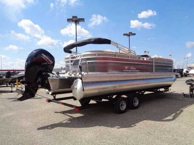 Slide: The Image of 2024 Sun Tracker Party Barge 24 DLX pontoon boat on trailer under blue sky. - 4