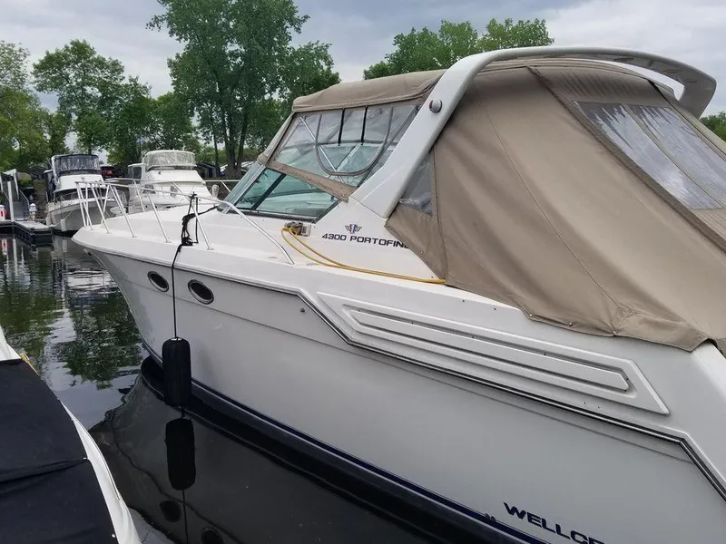 Slide: The Image of 1996 Wellcraft Portofino 43 boat docked in a marina, featuring a beige canopy. - 2
