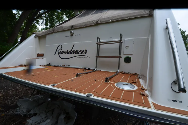Slide: The Image of 1996 Wellcraft Portofino 43 boat stern with "Riverdancer" name, docked in wooded area. - 32