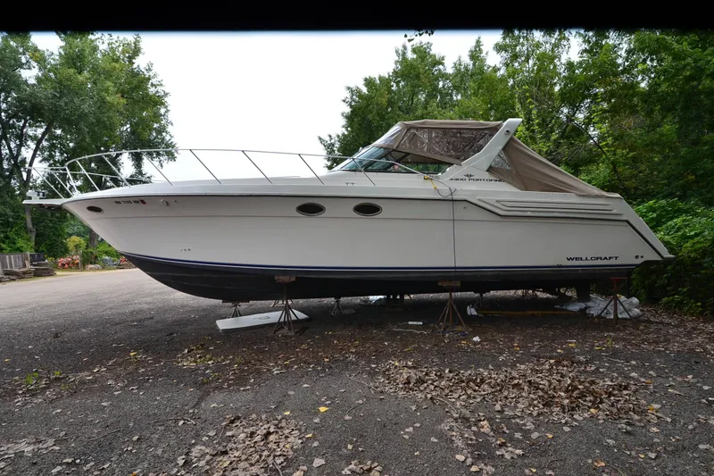 Slide: The Image of 1996 Wellcraft Portofino 43 boat on stands, surrounded by trees and leaves. - 5