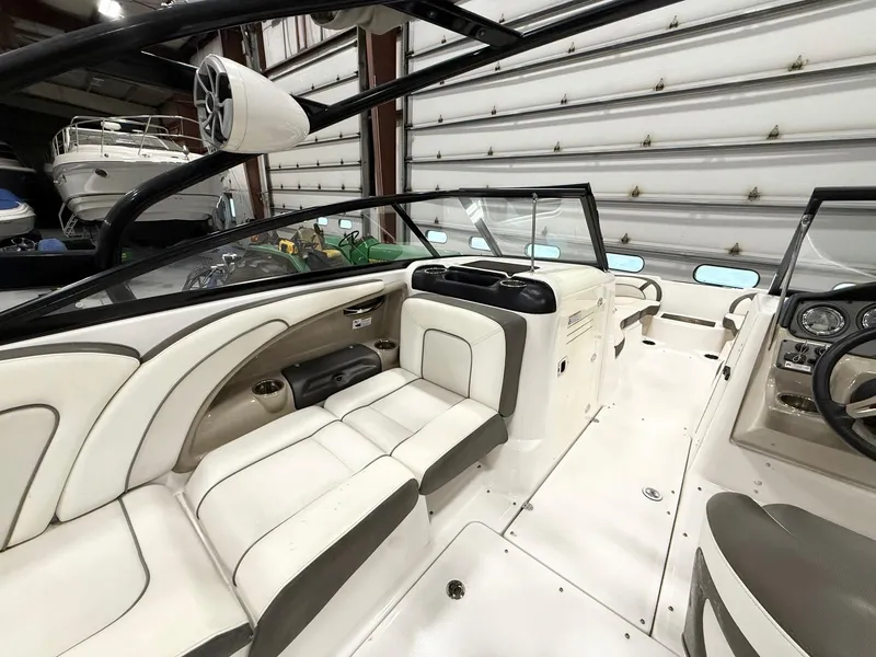 Slide: The Image of 2014 Yamaha Boats 242 Limited S interior with white seating and dashboard in a garage. - 12
