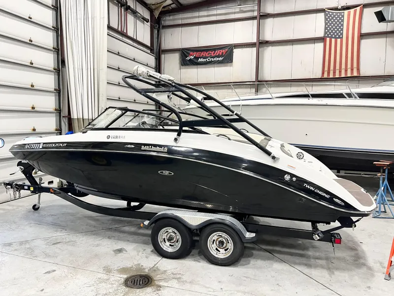 Slide: The Image of 2014 Yamaha Boats 242 Limited S in a garage, black and white design, on a trailer. - 2