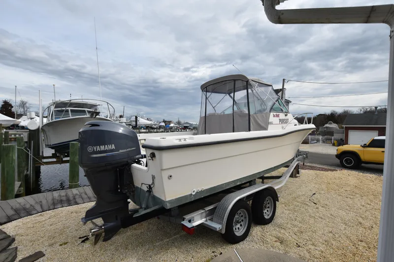 Slide: The Image of 1994 Pursuit 2350 boat on trailer with Yamaha outboard motor at marina. - 10
