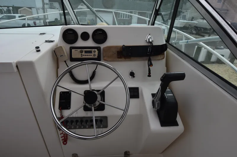 Slide: The Image of 1994 Pursuit 2350 boat helm with steering wheel, throttle, and control panel. - 17