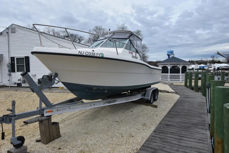 Slide: The Image of 1994 Pursuit 2350 boat on a trailer at a marina. - 3