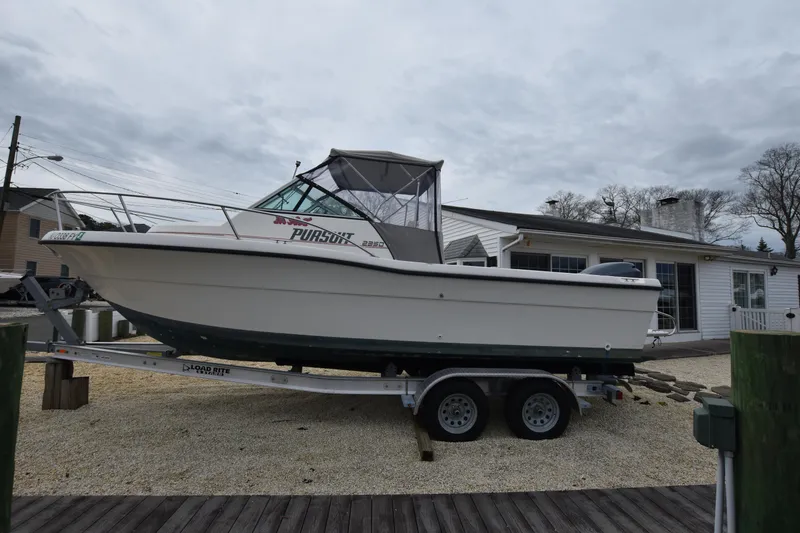 Slide: The Image of 1994 Pursuit 2350 boat on a trailer in front of a house. - 5