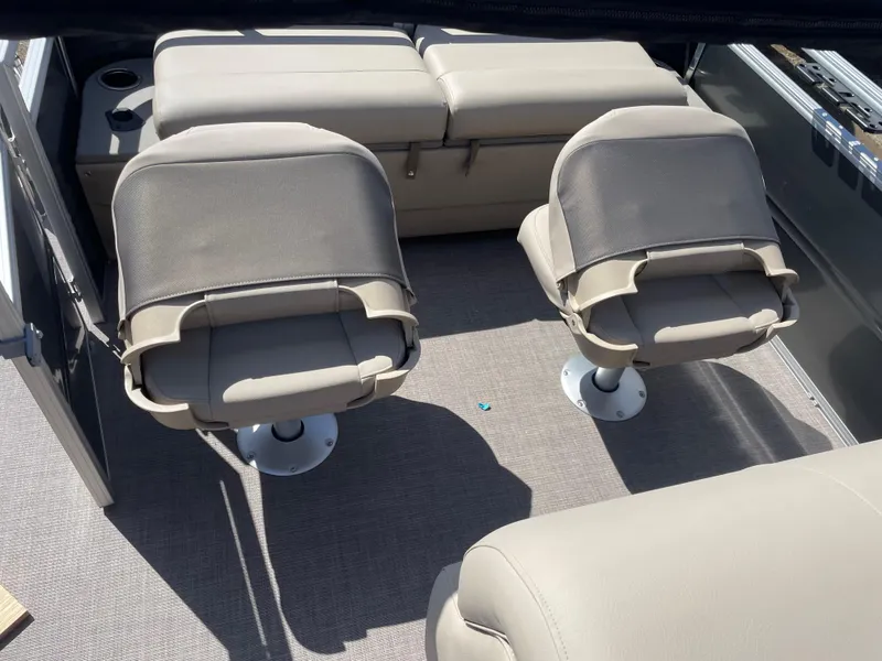 Slide: The Image of 2024 Sun Tracker Fishin' Barge 22 DLX interior with beige seating and fishing chairs. - 14