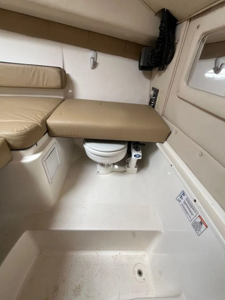 Slide: The Image of 2012 Striper 2601 Walkaround cabin interior with compact toilet and cushioned seating. - 12