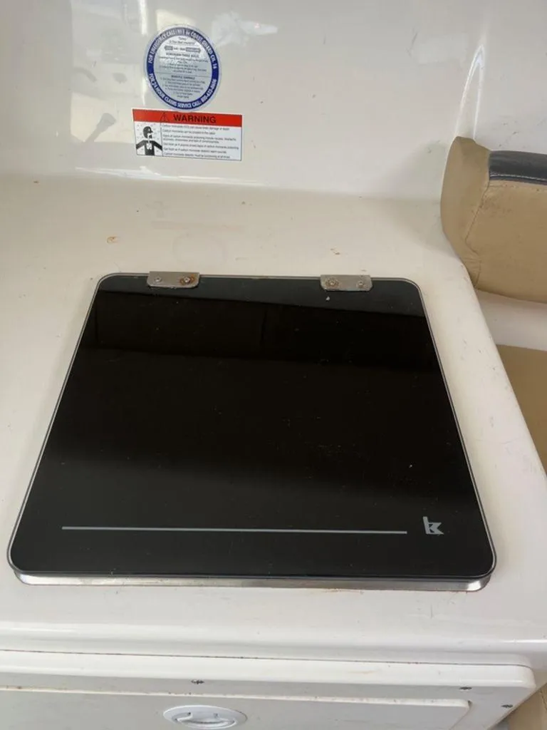 Slide: The Image of 2012 Striper 2601 Walkaround boat interior with a closed black stove cover. - 13