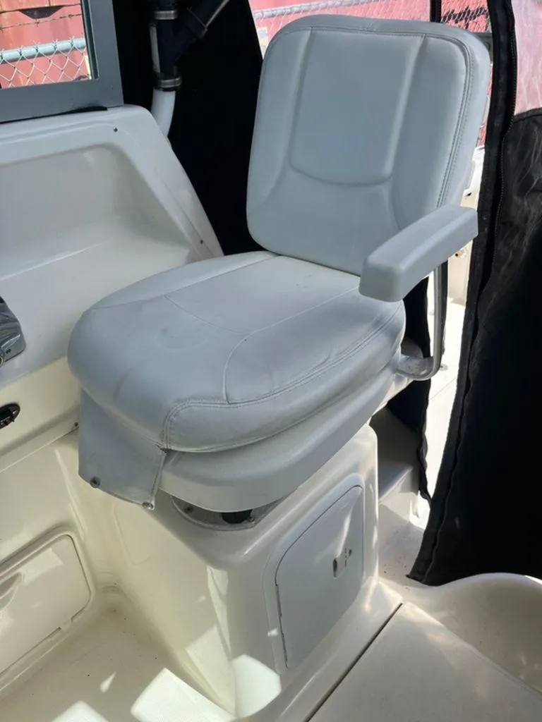 Slide: The Image of White captain's chair on 2012 Striper 2601 Walkaround boat, featuring armrest and storage compartment. - 6