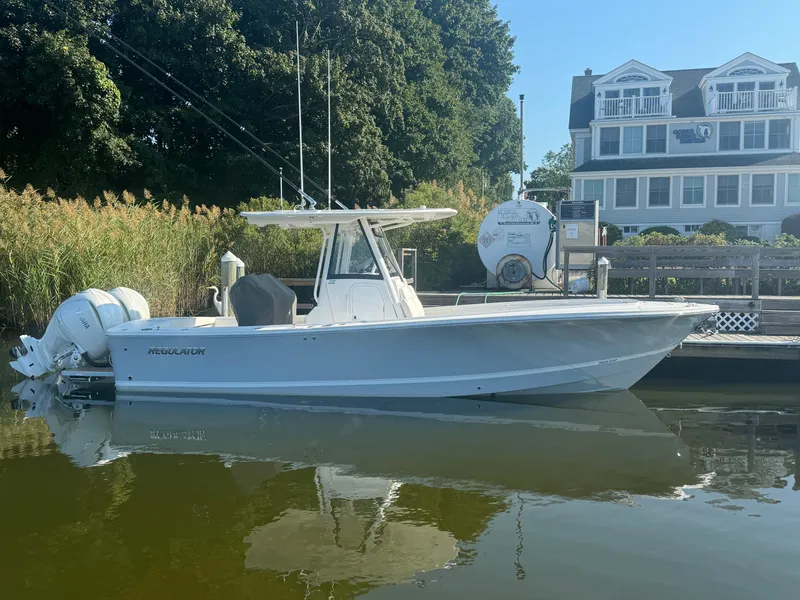 Slide: The Image of 2025 Regulator 28 boat docked by a waterfront house. - 2