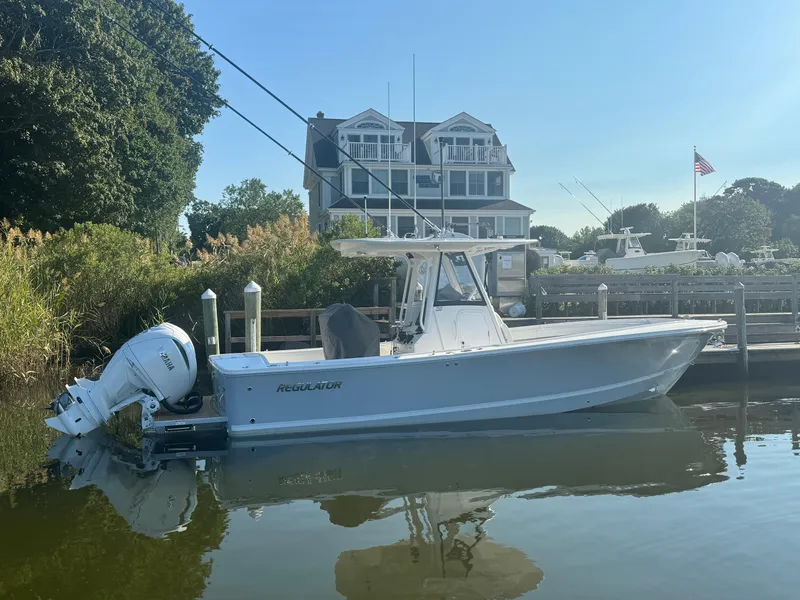 Slide: The Image of 2025 Regulator 28 boat docked by a waterfront house on a sunny day. - 3