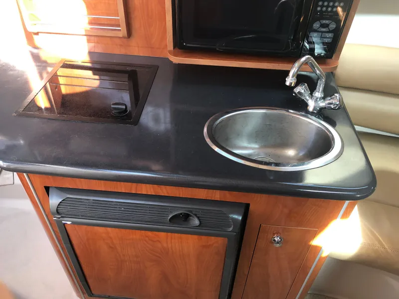 Slide: The Image of Compact kitchen area in a 2005 Doral Monticello boat with sink, stove, and microwave. - 11