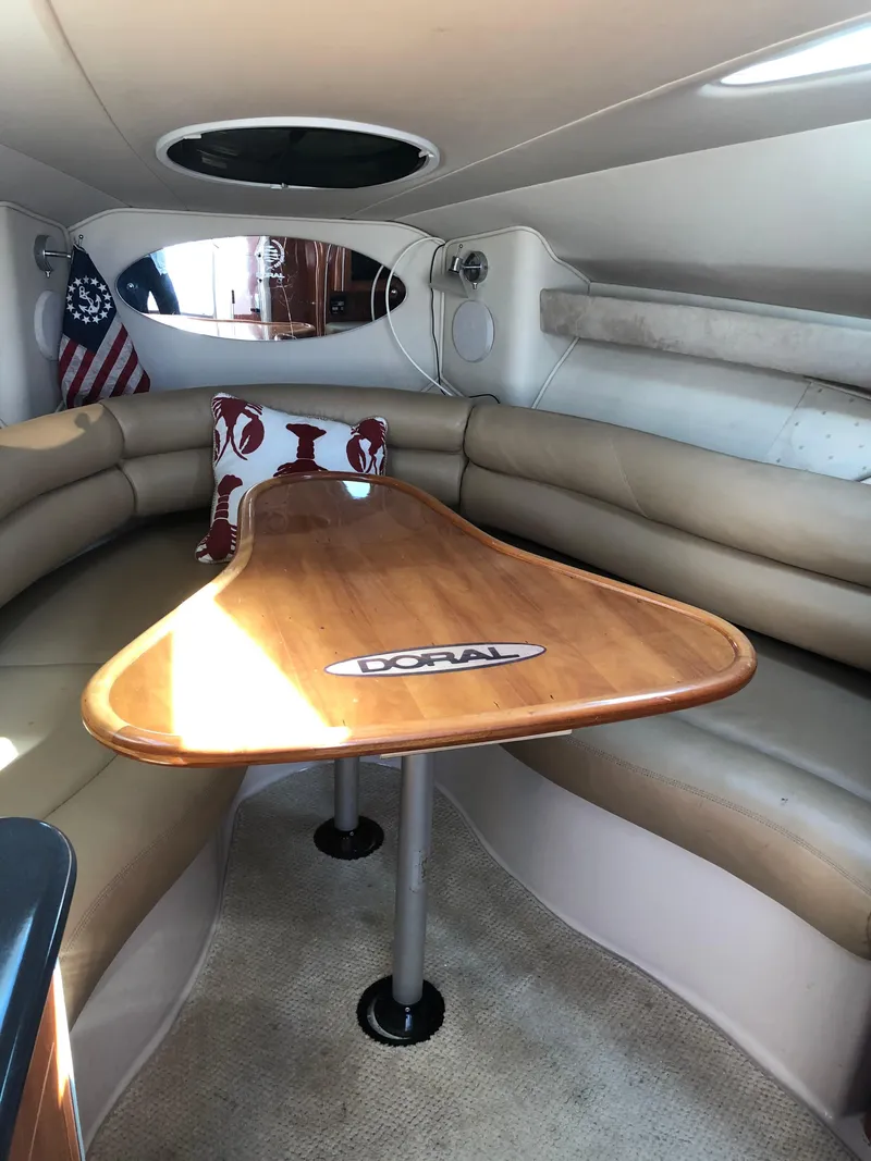 Slide: The Image of Interior of a 2005 Doral Monticello boat with a wooden table and cushioned seating. - 7