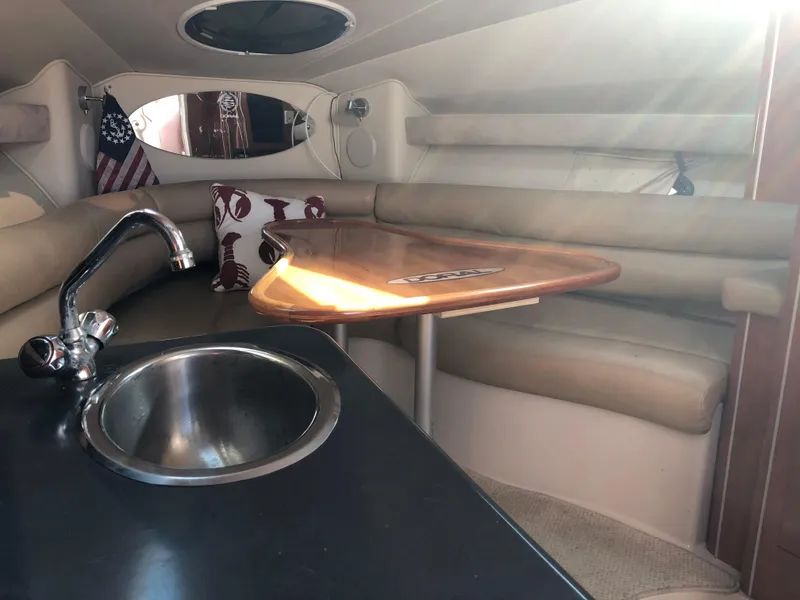 Slide: The Image of 2005 Doral Monticello boat interior with sink, wooden table, and cushioned seating. - 8