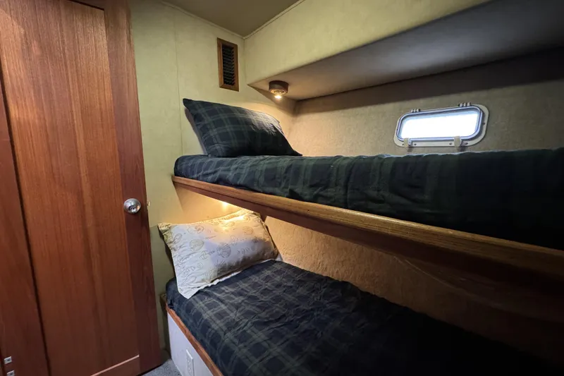 Slide: The Image of 1988 Chris-Craft 392 Commander cabin with cozy bunk beds and wooden door. - 12