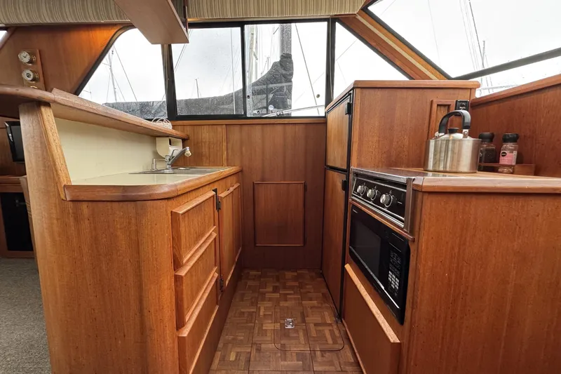 Slide: The Image of 1988 Chris-Craft 392 Commander yacht kitchen with wood cabinetry, stove, and sink. - 14