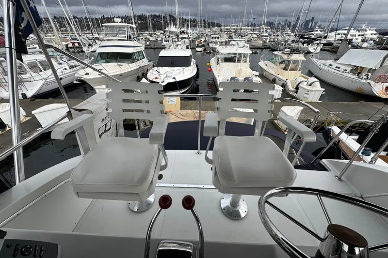Slide: The Image of 1988 Chris-Craft 392 Commander yacht helm with white chairs, overlooking marina. - 3