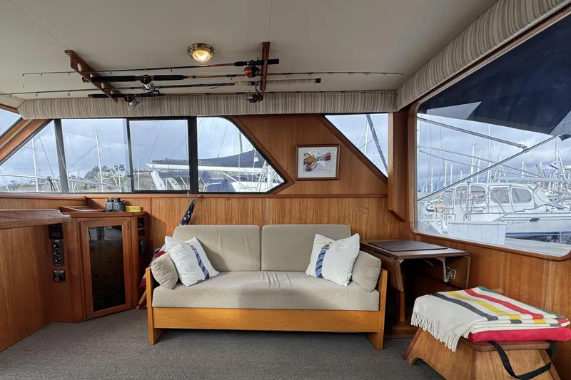 Slide: The Image of 1988 Chris-Craft 392 Commander interior with sofa, fishing rods, and marina view. - 5