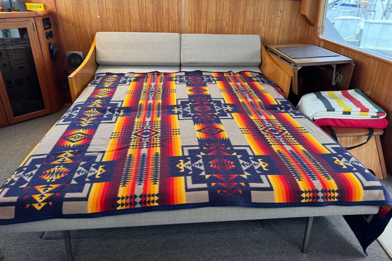Slide: The Image of 1988 Chris-Craft 392 Commander interior with colorful geometric-patterned blanket on a sofa bed. - 6