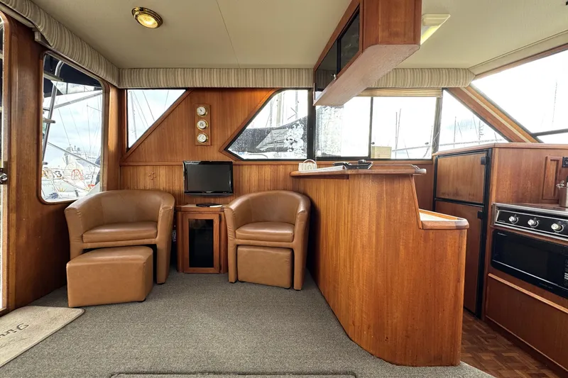 Slide: The Image of 1988 Chris-Craft 392 Commander interior with leather chairs, TV, and wooden cabinetry. - 7