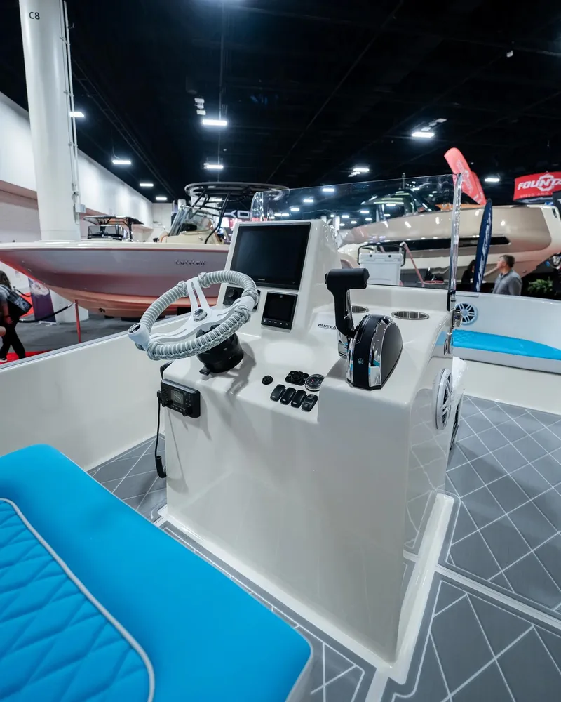 Slide: The Image of BlueCat 17 boat model 2024 interior with steering wheel and control panel at a boat show. - 6