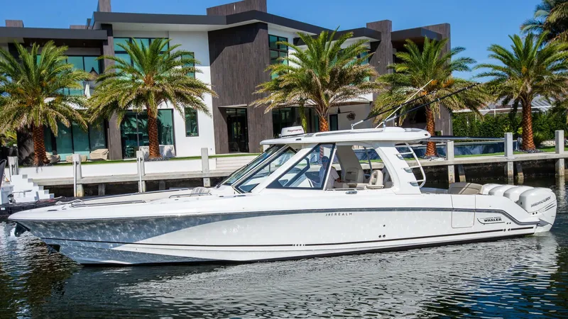 Slide: The Image of 2019 Boston Whaler 380 Realm boat docked near modern waterfront home. - 1