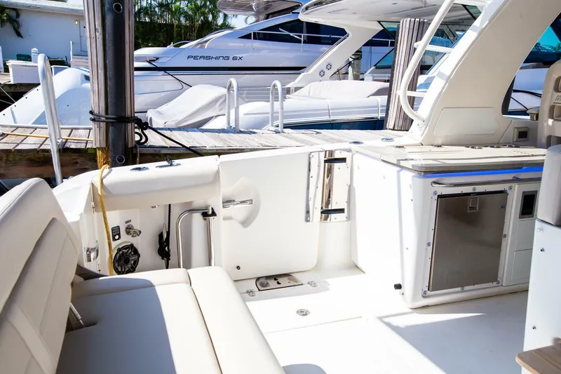 Slide: The Image of 2019 Boston Whaler 380 Realm boat interior with seating and docked yachts in the background. - 16