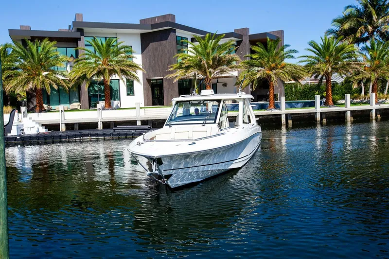 Slide: The Image of 2019 Boston Whaler 380 Realm boat docked near a modern waterfront home. - 2