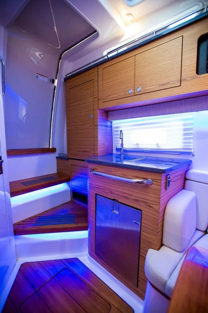 Slide: The Image of 2019 Boston Whaler 380 Realm interior cabin with modern kitchen and ambient lighting. - 36