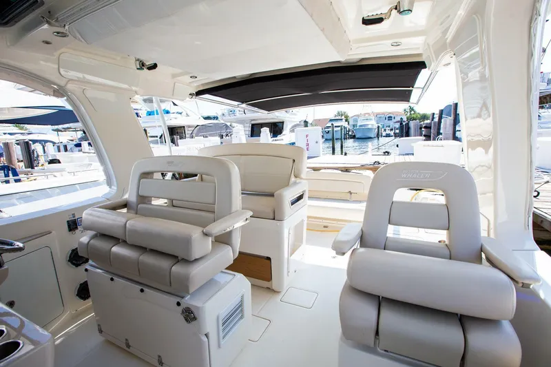 Slide: The Image of 2019 Boston Whaler 380 Realm interior with luxurious seating and marina view. - 9
