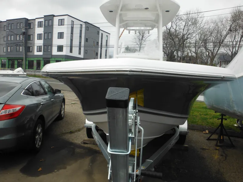 Slide: The Image of 2024 Tidewater 210 LXF boat on trailer, parked near a car and buildings. - 3