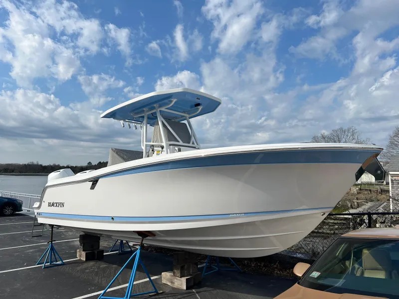 The Image of 2024 Blackfin 252 CC boat on stands, parked outdoors under a blue sky. - 0