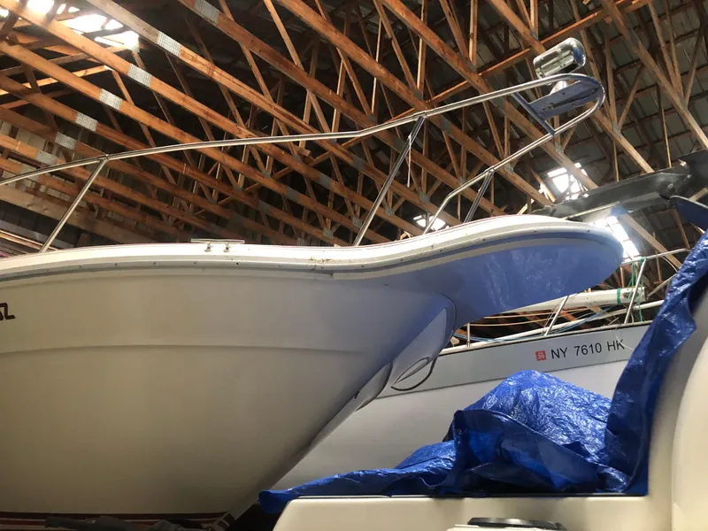 Slide: The Image of 1989 Sea Ray 280 Sundancer boat stored indoors, partially covered with blue tarp. - 3