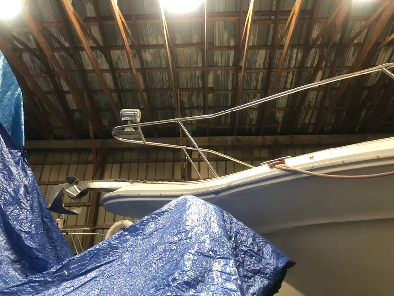Slide: The Image of 1989 Sea Ray 280 Sundancer boat partially covered in a blue tarp inside a warehouse. - 5