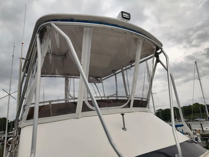 Slide: The Image of 1988 Trojan F32 Sedan boat with enclosed flybridge, docked under cloudy skies. - 11