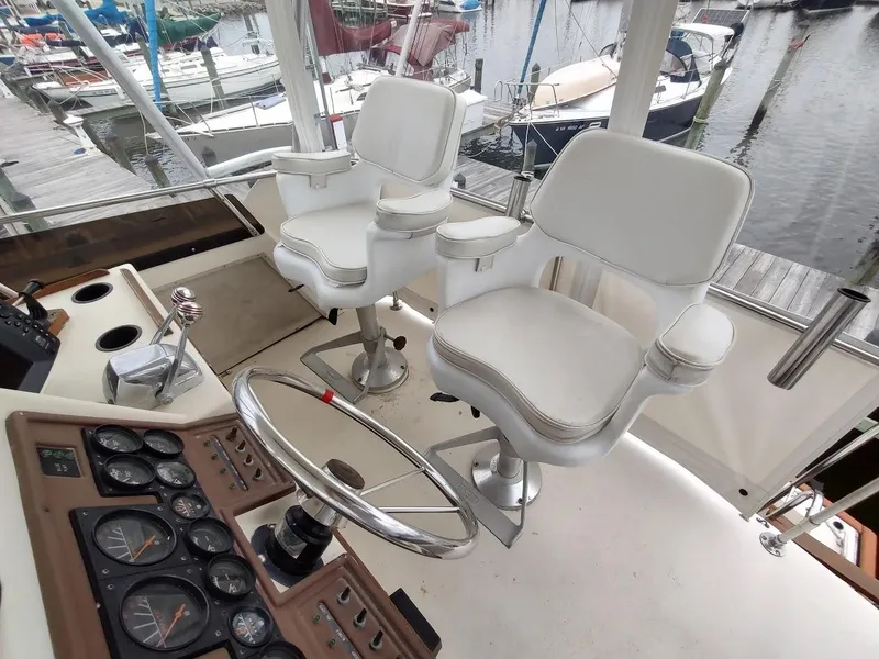 Slide: The Image of 1988 Trojan F32 Sedan cockpit with white captain chairs and control panel, docked at marina. - 16