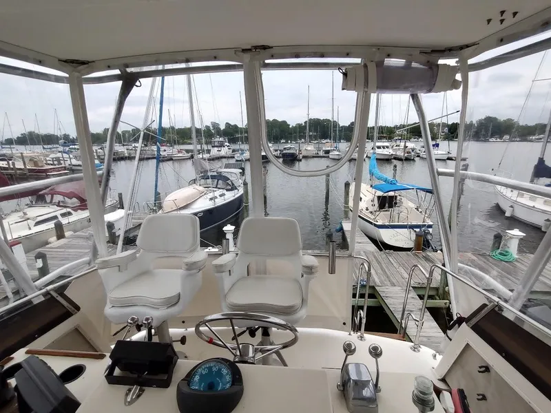 Slide: The Image of 1988 Trojan F32 Sedan boat interior with marina view, featuring helm and seating area. - 30