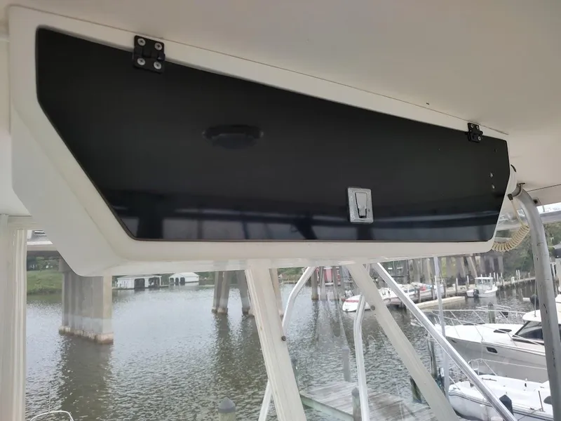 Slide: The Image of 1988 Trojan F32 Sedan boat interior with black storage compartment, docked by a marina. - 23