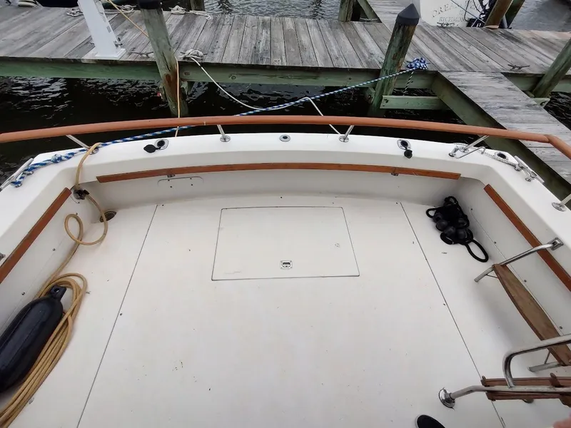 Slide: The Image of 1988 Trojan F32 Sedan boat deck with dock view, featuring ropes and wooden railings. - 31