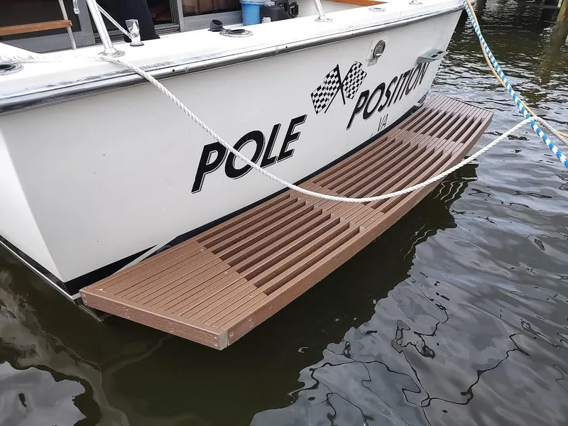 Slide: The Image of 1988 Trojan F32 Sedan boat with wooden swim platform, docked on calm water. - 4