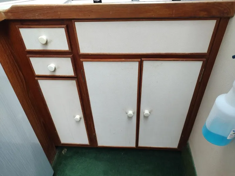 Slide: The Image of Wooden cabinet with white doors and knobs inside a 1988 Trojan F32 Sedan. - 49