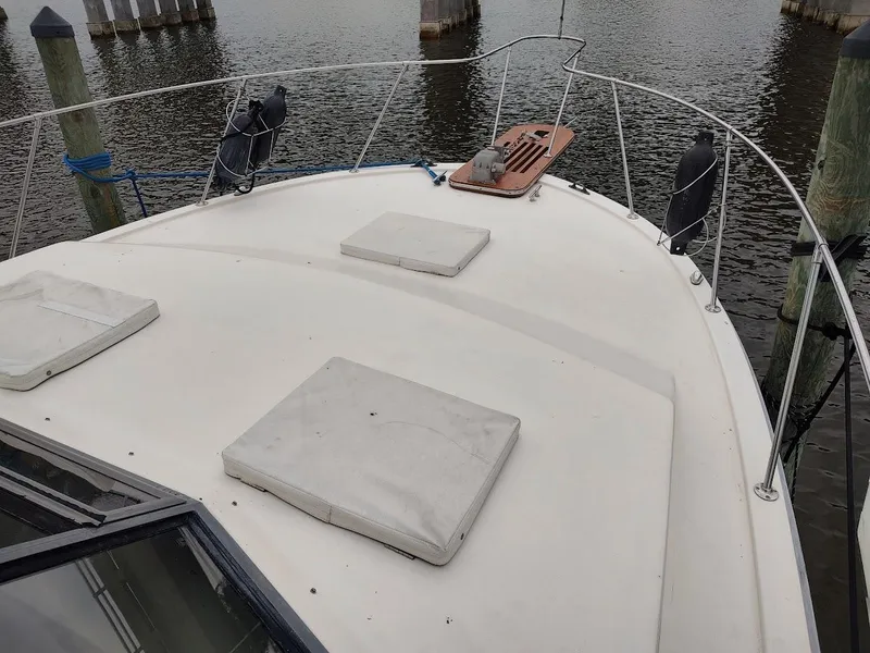 Slide: The Image of 1988 Trojan F32 Sedan boat deck with hatches, docked by wooden posts. - 6