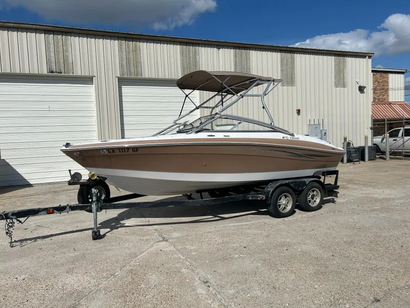 Slide: The Image of 2010 Four Winns H210 boat on a trailer in front of a warehouse. - 2