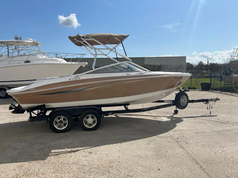 Slide: The Image of 2010 Four Winns H210 boat on a trailer under a clear blue sky. - 4