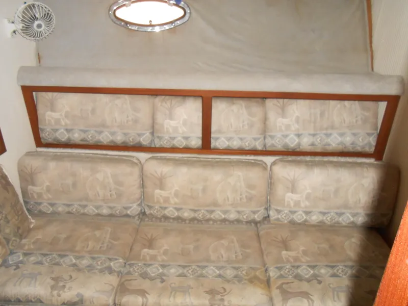 Slide: The Image of 1988 Cruisers Yachts 4280 Express Bridge interior with patterned sofa and porthole window. - 17
