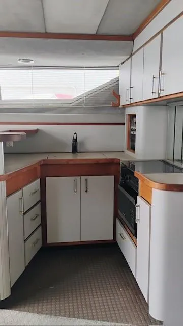 Slide: The Image of 1988 Cruisers Yachts 4280 Express Bridge kitchen with white cabinets and wood accents. - 39