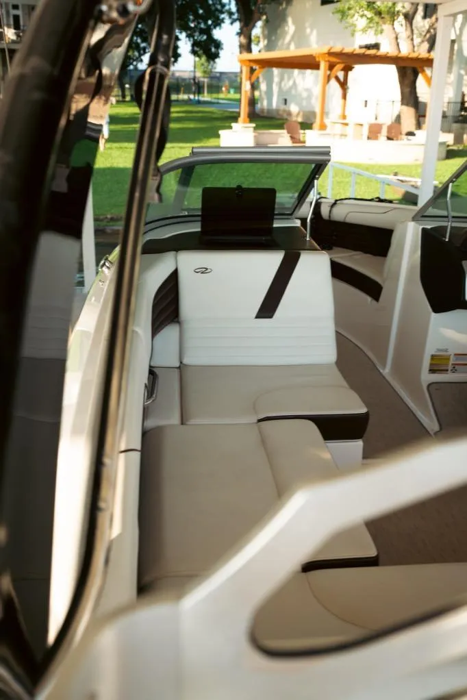 Slide: The Image of 2016 Regal 2100 Bowrider interior with white and black seating, outdoor setting. - 16